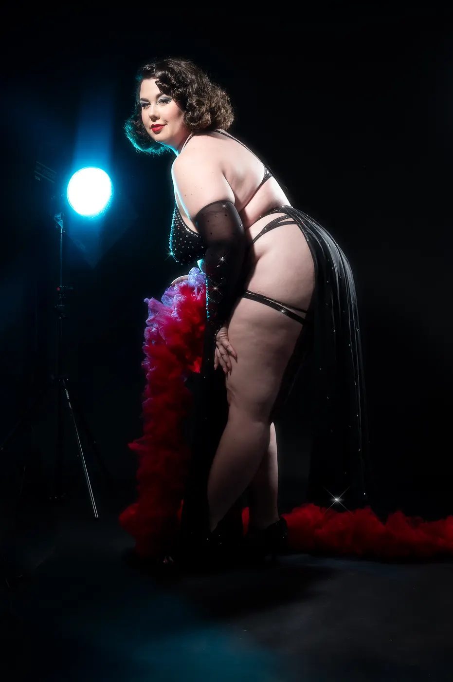 Burlesque dancer with a feather boa under a blue stage spotlight